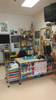 an office with many items on the desk and shelves full of books, papers, magazines