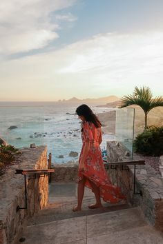 a woman walking up some steps near the ocean