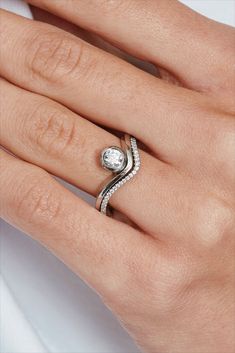 a woman's hand with a diamond ring on her left hand and the other hand holding an engagement ring