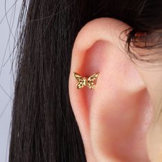 a close up of a person's ear with a small gold butterfly on it