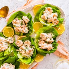 lettuce wraps with shrimp and oranges on a white plate next to silverware