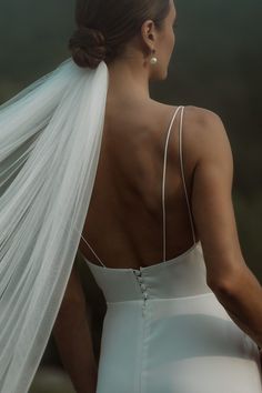 the back of a bride's wedding dress with her veil blowing in the wind