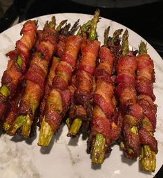 bacon wrapped asparagus on a white plate with marble counter top and black background