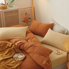 a bed with an orange comforter and pillows on top of it in a bedroom