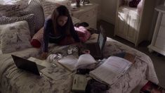 a woman sitting on top of a bed with lots of books in front of her