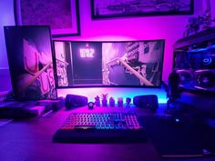 a desk with two monitors, keyboard and mouse in front of purple lighting on the wall