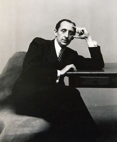 a black and white photo of a man sitting at a desk with his hand on his head