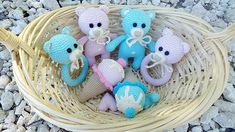 small crocheted stuffed animals sitting in a basket on the ground next to rocks