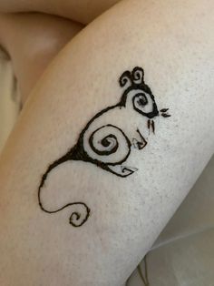 a woman's leg with a cat tattoo on the side of her thigh, which is drawn in black ink