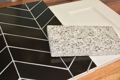 a black and white tiled counter top next to a wooden table with a tile design on it