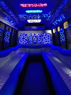 the inside of a bus with blue lights and couches on it's sides