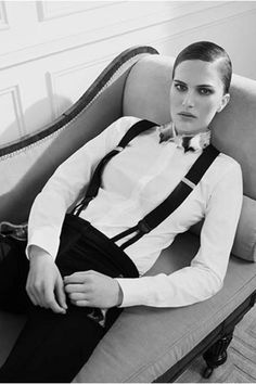 black and white photograph of a man sitting on a couch wearing suspenders, shirt and tie