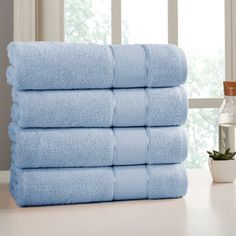 a stack of blue towels sitting on top of a table next to a potted plant