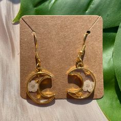 These delicate golden crescent moon shaped earrings feature real pressed blossom flowers encased in resin. Small and pretty, they will turn heads wherever you go as they are one of a kind and uniquely handmade with real dried flowers, so no two pairs will ever be identical.  Perfect gift for the lover of or all things celestial or nature.  These are dangle earrings on nickel and lead free gold plated earring hooks.  This listing is for the white blossoms, there are more colours available in my s White Crescent Earrings As Gift, White Crescent Earrings For A Gift, White Crescent Earrings For Gift, Hypoallergenic Gold Flower Earrings With Resin, Gold Round Flower Earrings In Resin, Gold Resin Earrings With Birth Flower, Gold Resin Earrings With Birth Flower Detail, Gold Round Resin Flower Earrings, Gold Hypoallergenic Resin Flower Earrings