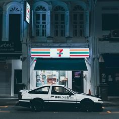 a white car parked in front of a building at night with an italian flag awning