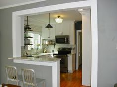 an open kitchen with white cabinets and stainless steel appliances, along with hardwood flooring