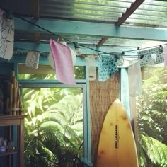 a surfboard is hanging from a clothesline in a room with plants and trees