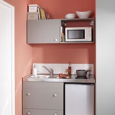 a small kitchen with red walls and white appliances on the counter top, as well as silver cabinets