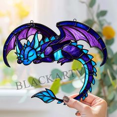 a hand holding up a stained glass dragon