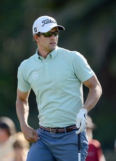 a man wearing sunglasses and holding a golf club in his hand while standing on the green