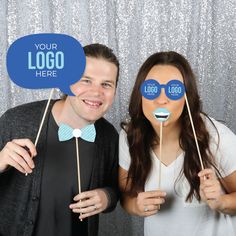 a man and woman posing for a photo booth with their logo stickers on them