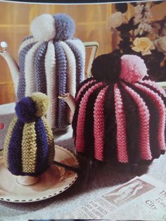 two knitted tea cosies sitting next to each other on top of a plate