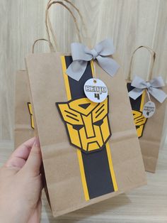 two brown paper bags with yellow and black designs on them, one has a gray bow