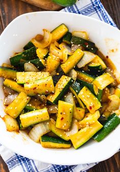 a white bowl filled with zucchini and other vegetables