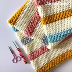 crocheted dishcloths and scissors on a table with knitting needles next to them