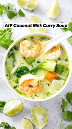 a white bowl filled with soup and garnished with limes, cilantro, carrots, and shrimp