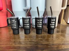 four coffee mugs sitting next to each other on a wooden table with cups in the background