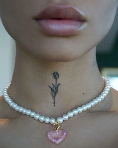 a close up of a person wearing a necklace with a flower and heart on it