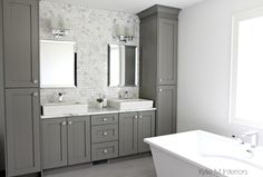 a large bathroom with two sinks and gray cabinets