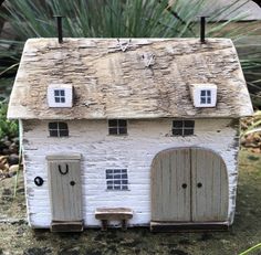 a small white brick house with two doors and windows on top of a stone slab