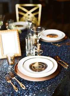 the table is set with plates, silverware and gold utensils for an elegant dinner