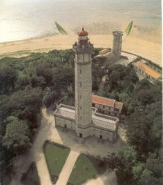 an aerial view of a lighthouse in the middle of trees and sand on the beach