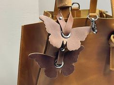 a brown leather bag with a butterfly on the front and two metal hooks attached to it