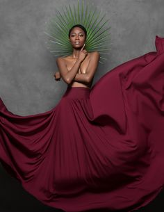 a woman in a long red dress posing with her hands on her chest and arms crossed