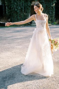 a bride and groom hold hands as they walk down the street