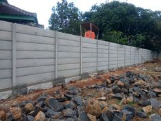 a concrete fence with rocks in front of it