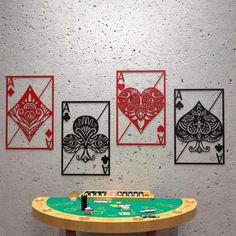 four playing cards are hanging on the wall next to a table with a green top