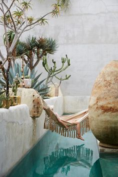 a woman laying in a hammock on top of a pool next to plants