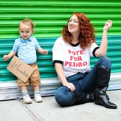 a woman sitting on the ground next to a little boy