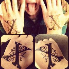 a man with two different tattoos on his hands and the other hand covering his eyes