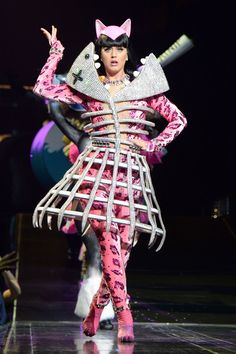 a woman in pink and white costume walking down a runway