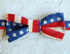 a red, white and blue bow tie laying on top of a cement wall with stars