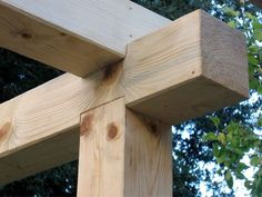 a close up of a wooden cross with trees in the background