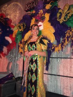 a woman standing in front of a mardi gras display wearing a colorful costume