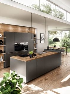 a modern kitchen with an island counter and wooden flooring, along with open shelving