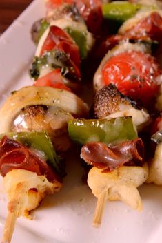 a white plate topped with meat and veggies on skewers